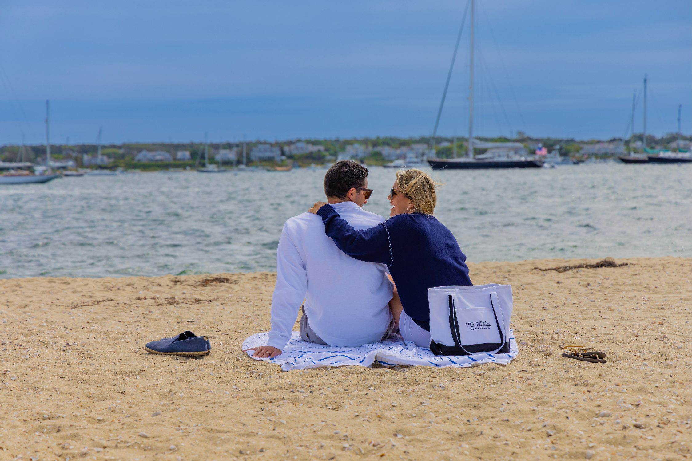 A Couple Sits Together On The Beach Looking Into Each Other's Eyes